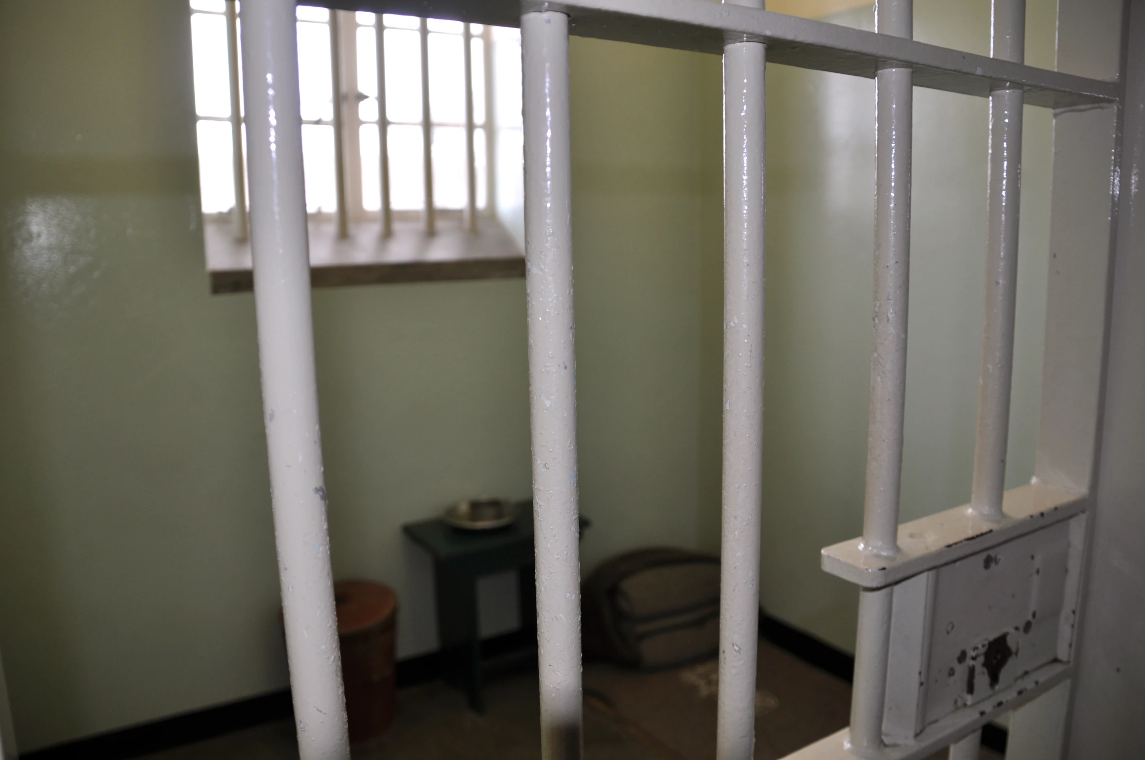 a prison cell with bars to the door and the window on the right