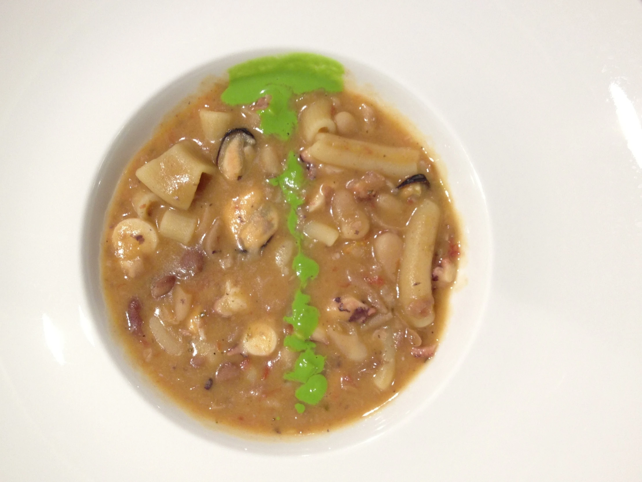 a white plate with noodles, mushrooms and broth