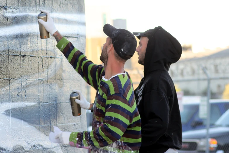 two people painting a large stone structure on the side of the road