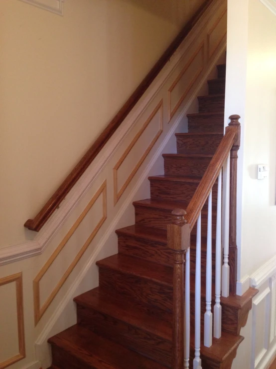 a wooden staircase with white railing and wooden handrail