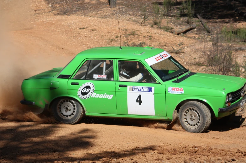 a green car with the number 4 going through dirt