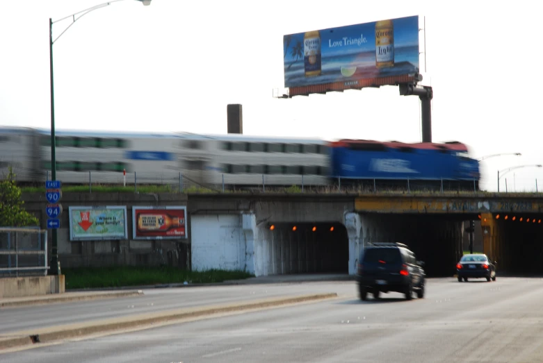 a train crossing under an overpass on a highway