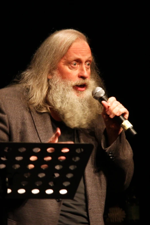 a man standing at a microphone in front of a black background