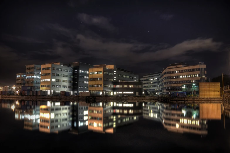 buildings lit up by night reflected in a body of water