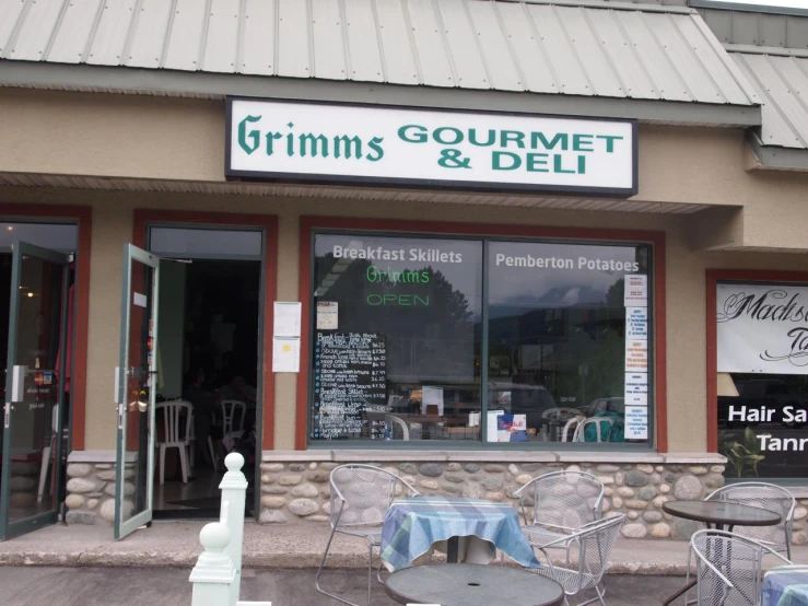 a store front with tables and chairs outside it