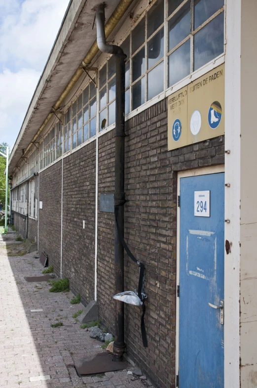 an old building with a blue door and metal pipe