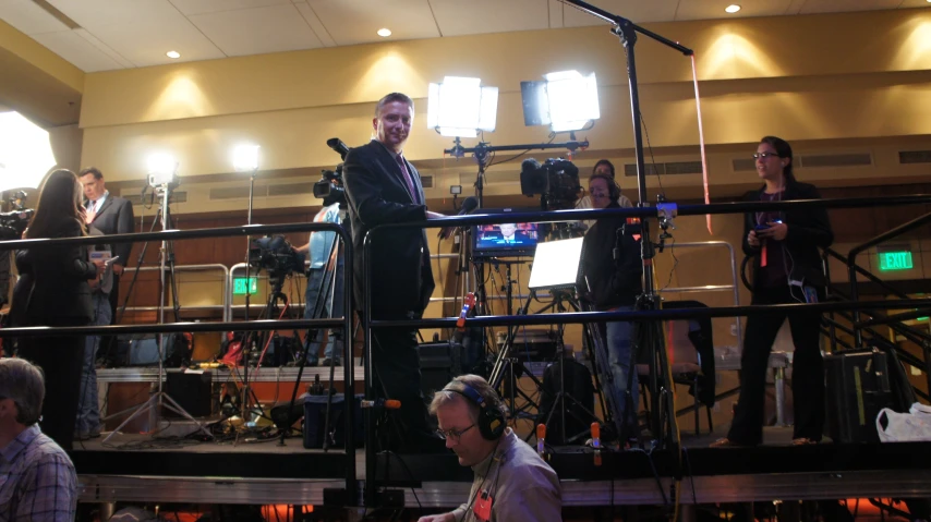 a man standing in a recording studio while other people stand around