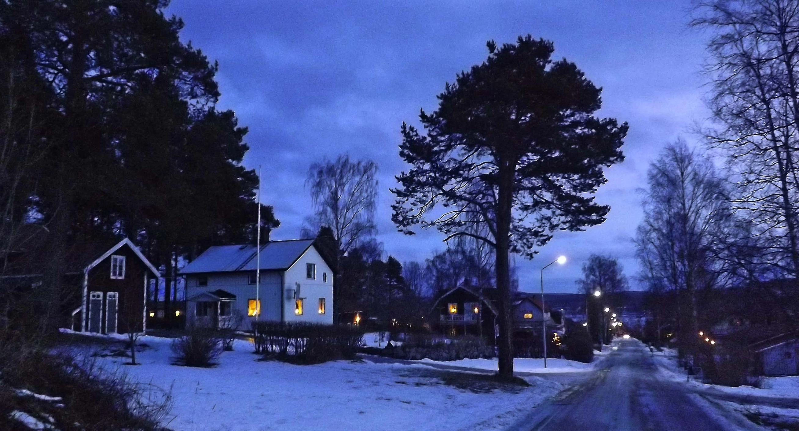 a snow covered street in front of a white building