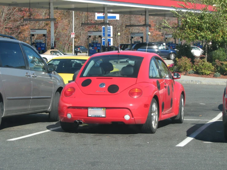 a red car sits parked near two other cars in a parking space