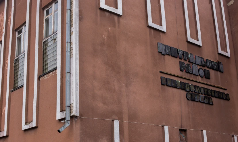 a large brown building has white windows and an inscription on the side