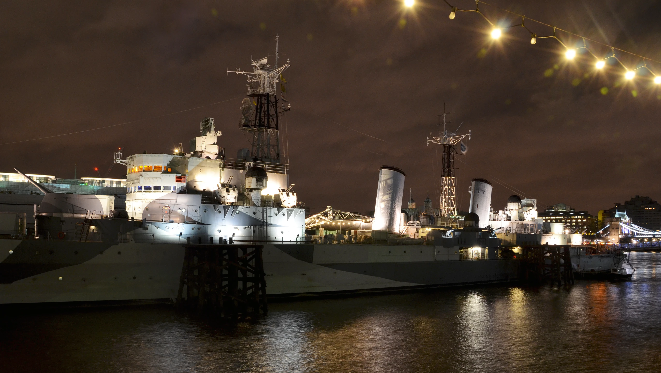 military ships are parked at the dock at night