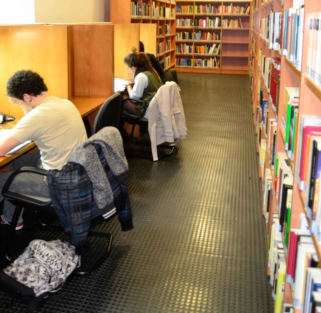 some people sit at tables in front of bookshelves