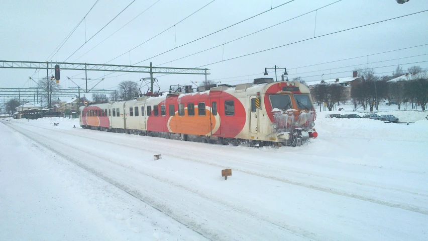 a train on tracks near an intersection, with snow falling all around