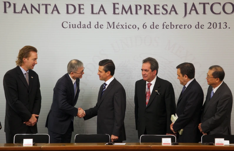 a group of men shake hands at a table