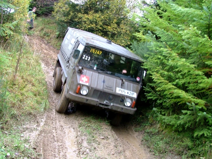 a humongous vehicle traveling up a dirt road in the woods