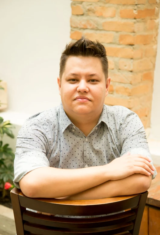 a man in a shirt sits on a chair with his arms folded