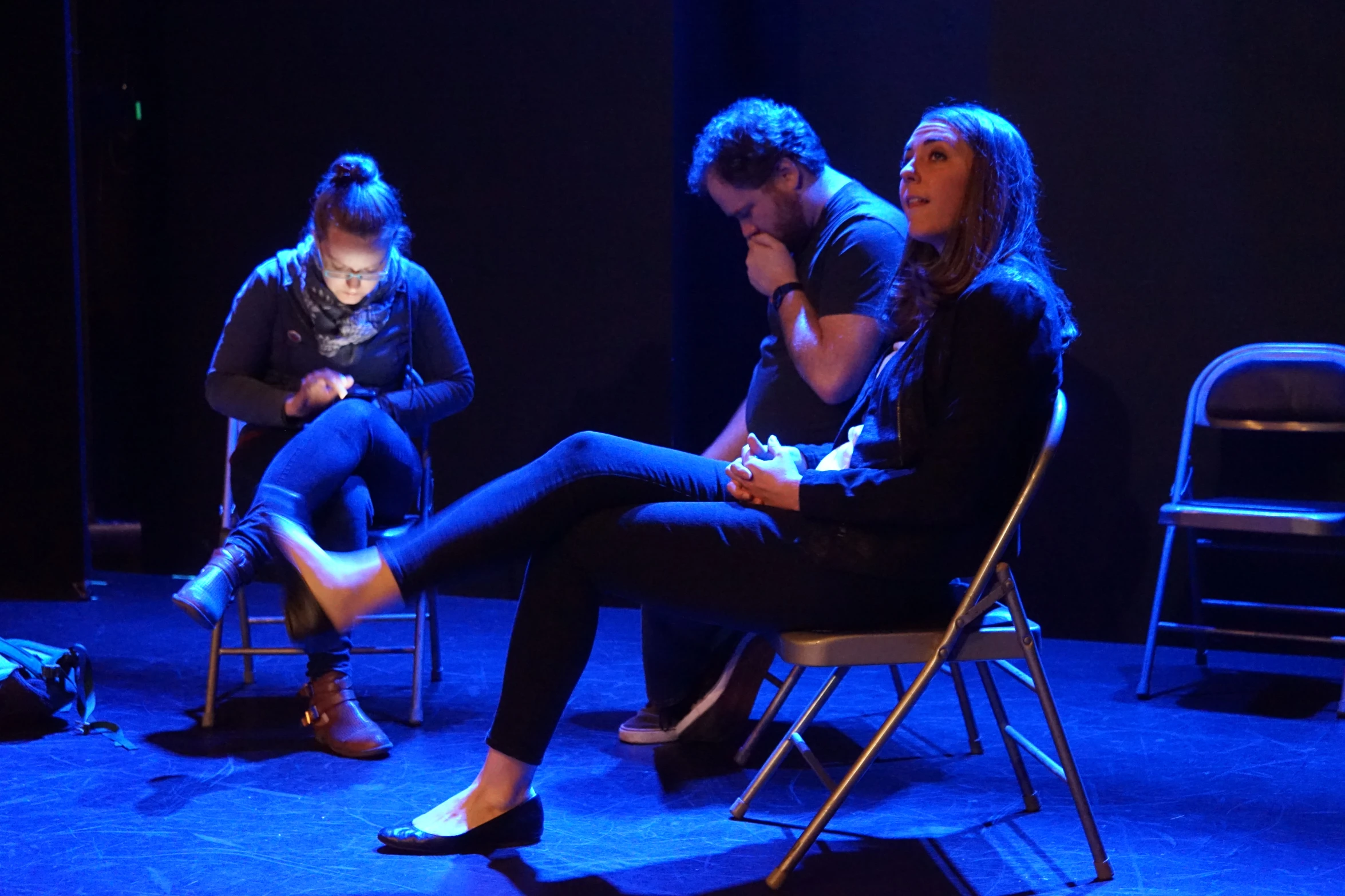 a man, a woman and a  sitting in chairs in a blue light