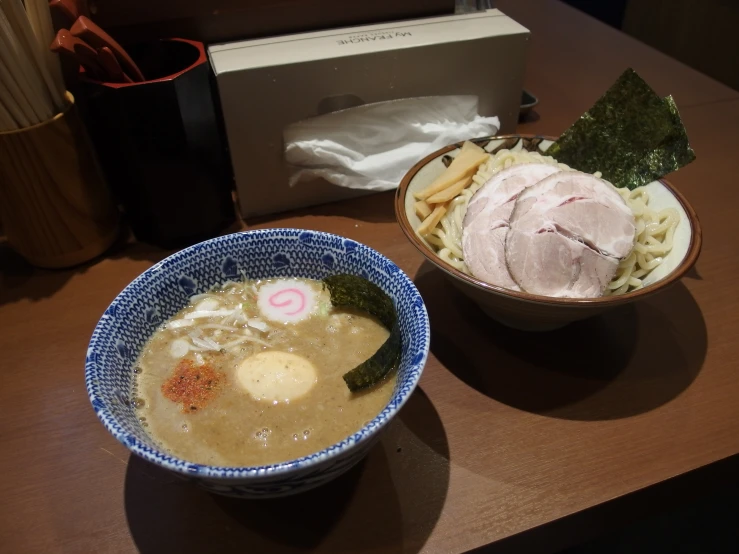 a bowl of soup next to a container with meat