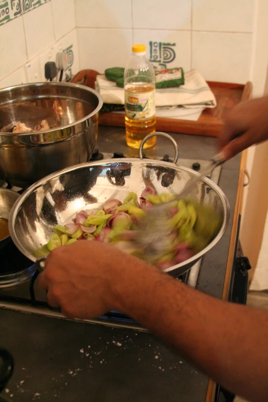 a cook stirs food onto a stainless steel bowl