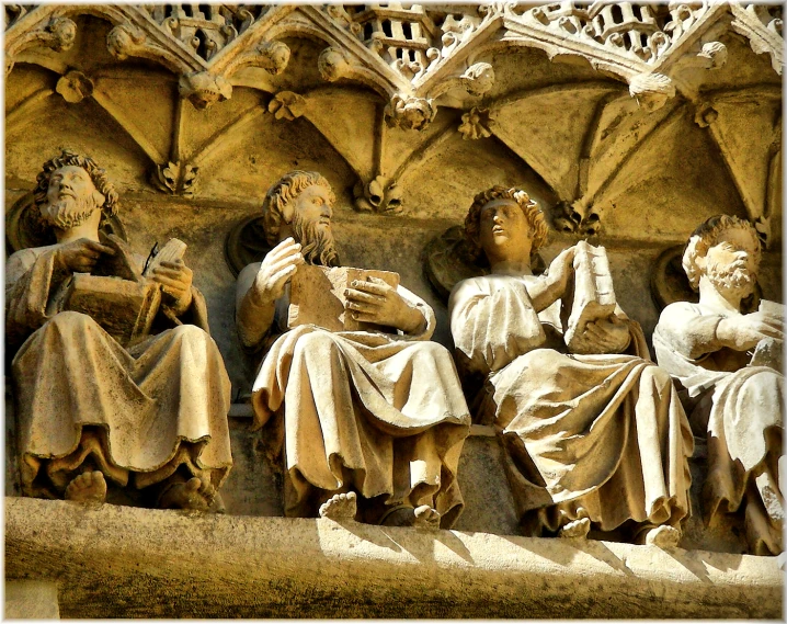 statues of women, books, and men in front of a building