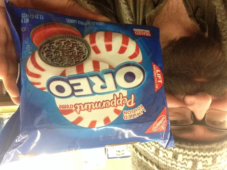 man wearing a knit hat holding up a bag of oreo