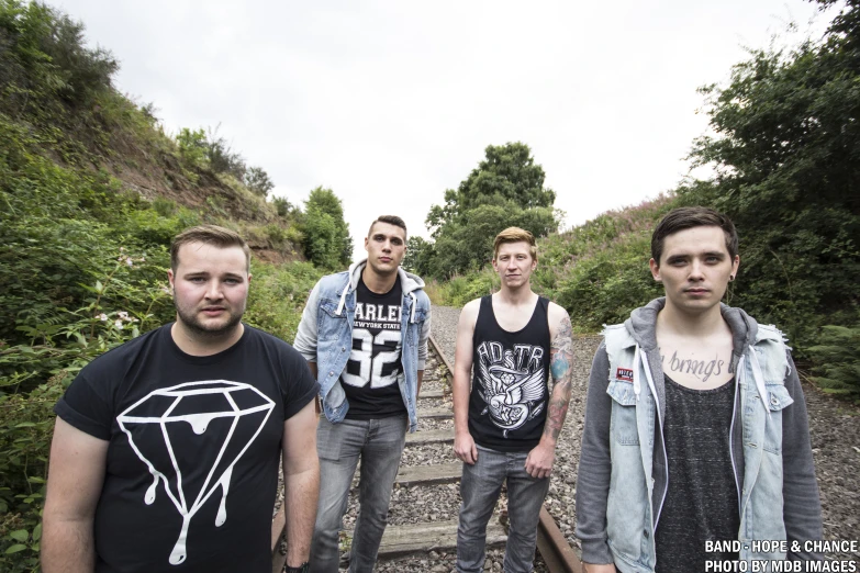 a group of guys walking across train tracks in the countryside