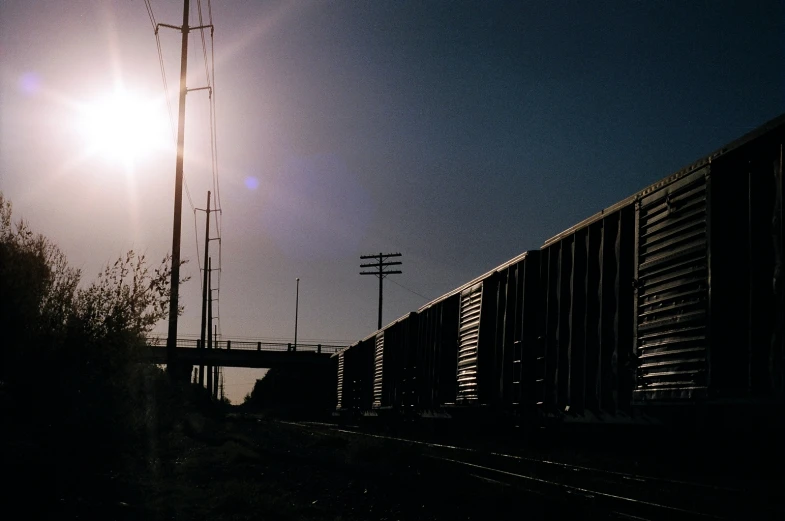 the sun is shining on the side of a train traveling on the railroad tracks