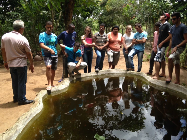 a group of people standing in front of a small pond