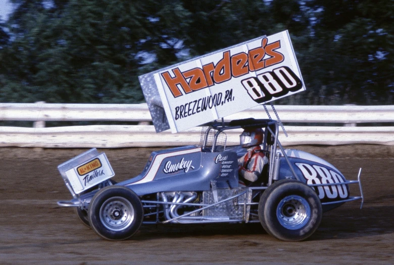 a car sitting in the dirt with a sign on top of it