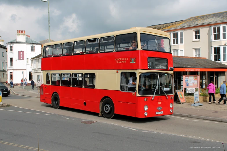 the red double decker bus is stopped on the road