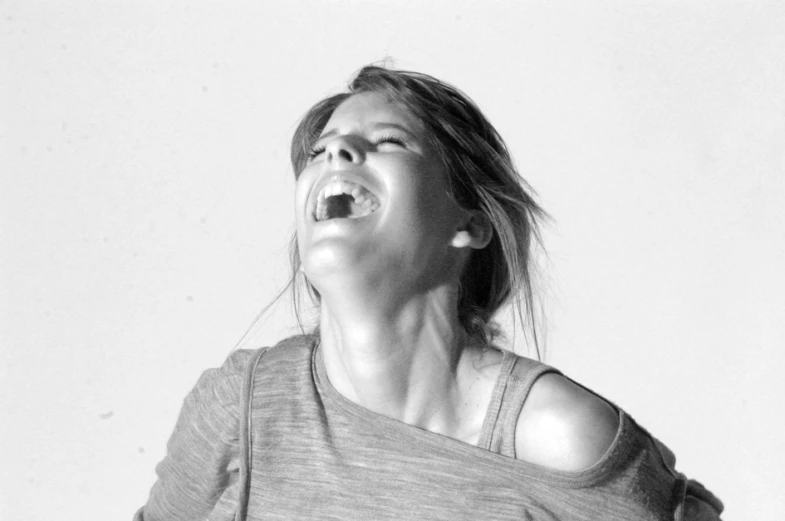 a woman laughing and yelling in a white room