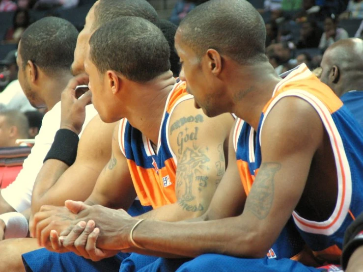 three basketball players sitting in the middle of a bench