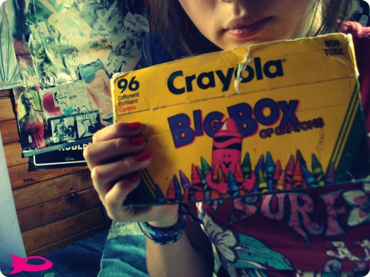 a little girl holding a large yellow box for crayola