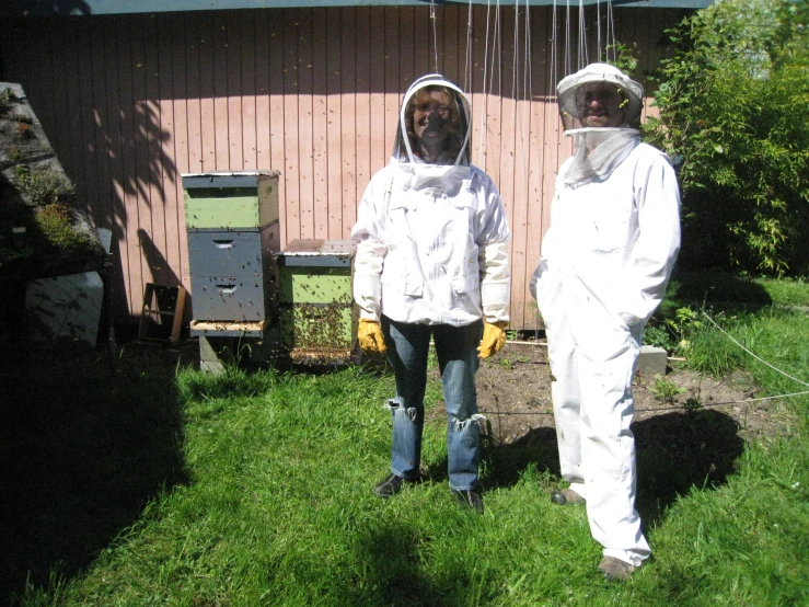 two people in bee suits standing on grass