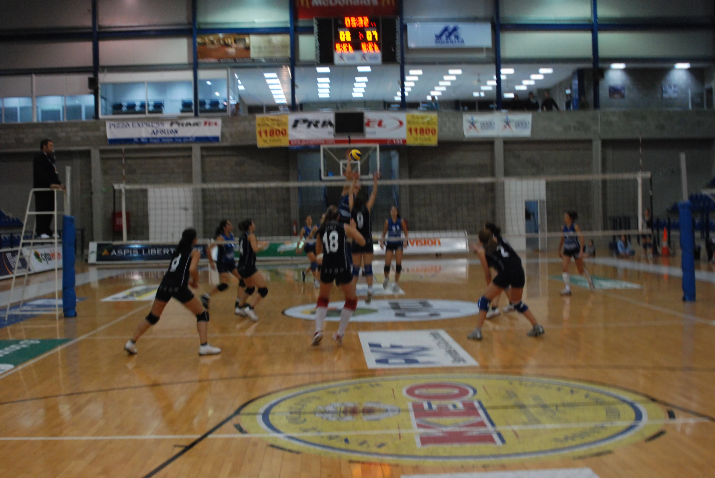 women play volley ball on the court in an indoor gymnasium