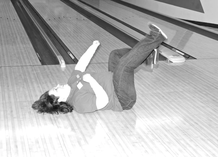 a man lying on a skateboard in a bowling alley