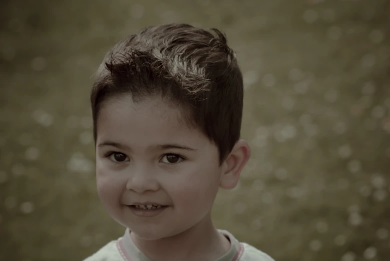 a boy smiling for a pograph wearing a white shirt