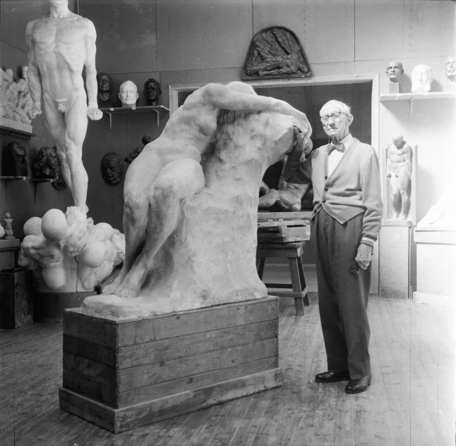 an older man standing next to a sculpture