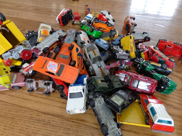 pile of toy cars and trucks on a wooden floor