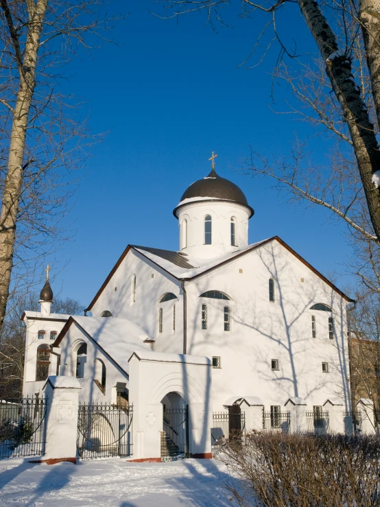 an old church with a snow covered field in front