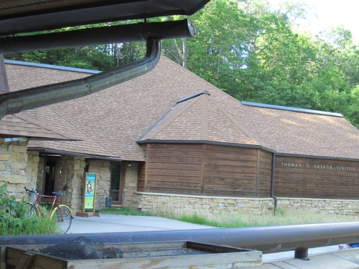 a large wooden building with two windows next to a fence