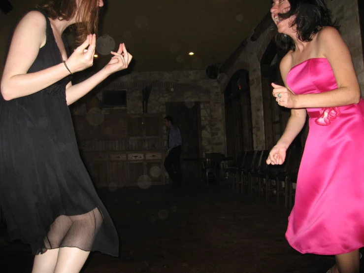 two women in dresses standing together, one in a black and the other in pink