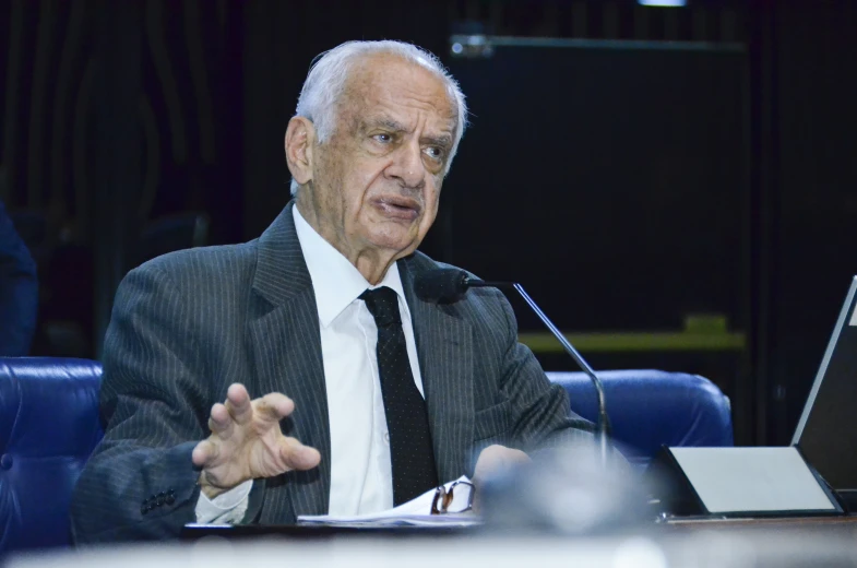 a man sitting at a desk with his hand outstretched