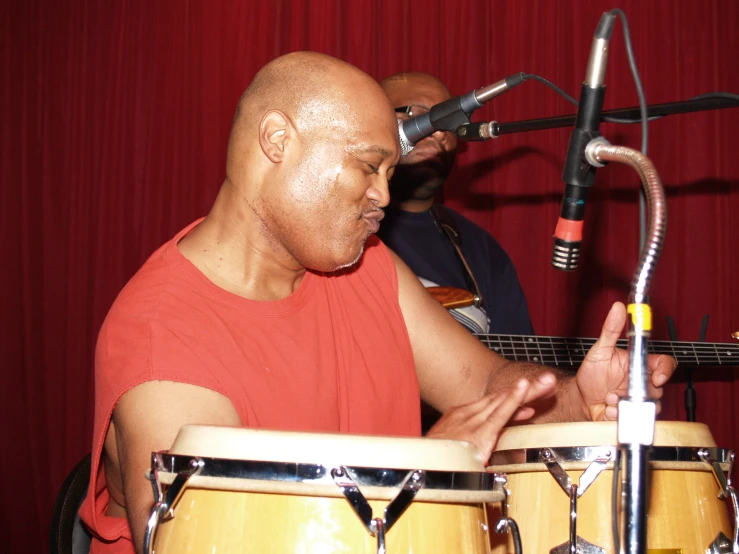 a bald man is playing the drums in front of a microphone