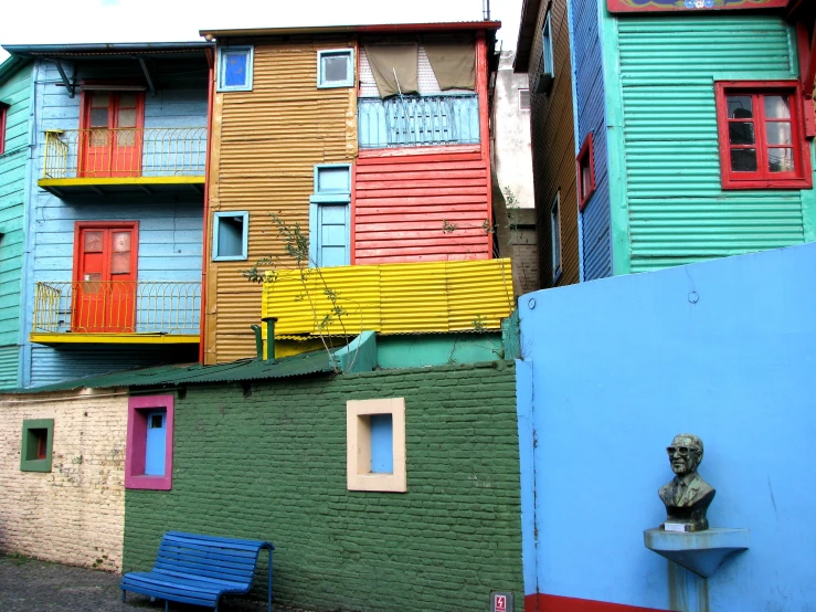 several multicolored buildings and one man sits near the wall