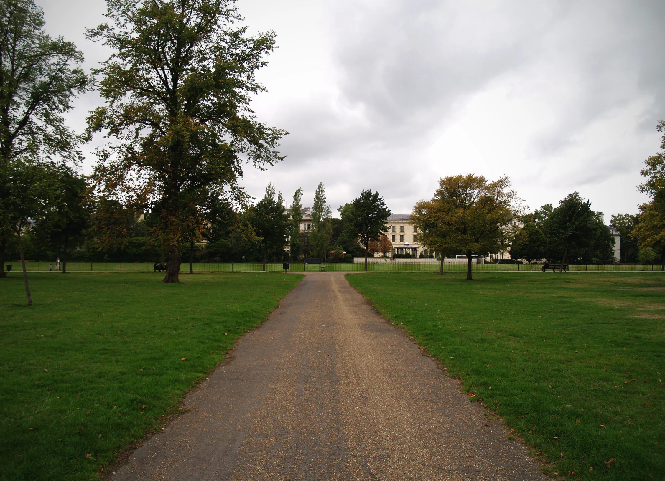 a stone walkway leading to a huge home in the distance