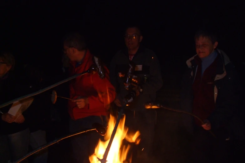 a couple of people standing next to a fire with a hose on it