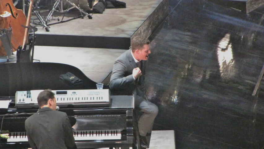 a man in a gray suit playing a keyboard on stage