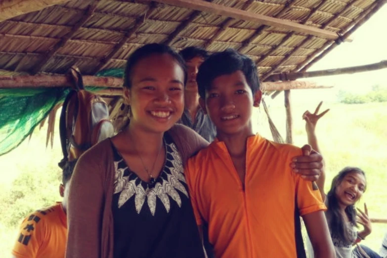 two people pose for a po under a hut