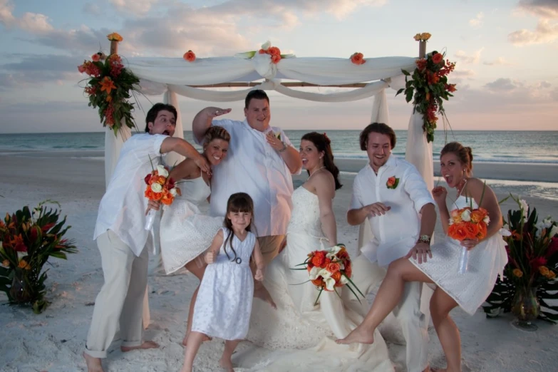 a wedding party poses on the beach for a po